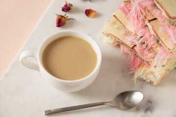 Tasty trendy breakfast with handicraft coffee and pink chocolate with airy filling white and pink pismaniye on marble board. Close up.
