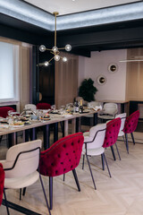 An elegant dining room interior featuring stylish chairs accompanied by a modern lighting design that enhances the overall aesthetic, creating a visually appealing and inviting atmosphere