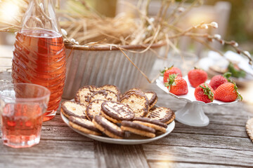 Red punch with fresh strawberry. Non-alcoholic summer drink with chocolate cookies on a garden terrace. Close-up with short depth of field.