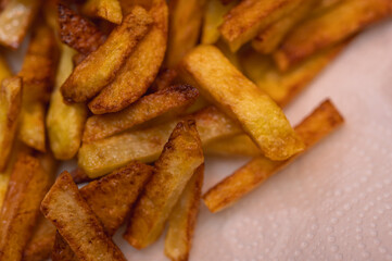 Golden crispy potato wedges sprinkled with sea salt, close-up. Perfect comfort food concept, perfect for fast food menus, advertising and food blogs, selective focus