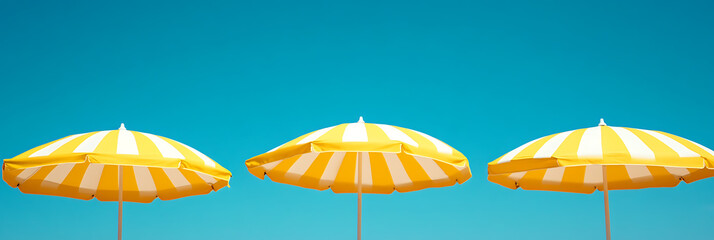 Yellow and white striped beach umbrellas offer shade against a vibrant blue sky, capturing the essence of summer vacations.