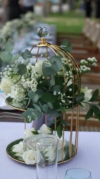 Elegant floral arrangement in a decorative birdcage at an outdoor setting