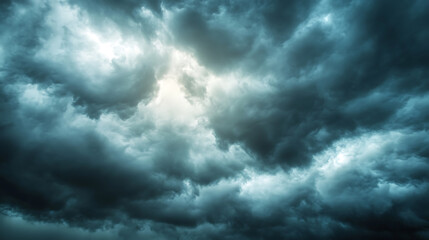 Dark dramatic sky with black storm clouds before rain or snow as abstract background, extreme weather, sun shines through clouds