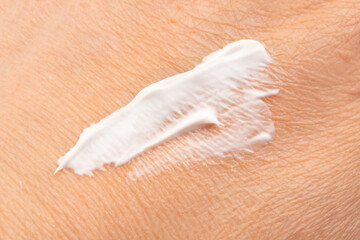 Applying skin cream close up. Body care lotion smear on dry skin, skincare moisturizer cosmetics