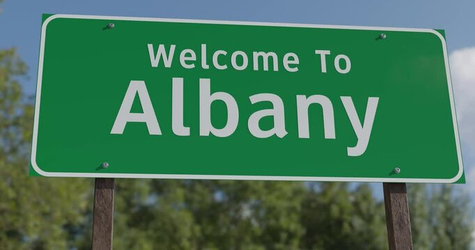 Driving By A Welcome To Albany, New York Green Road Sign Against a Blue Sky and Clouds - United States Capital Series.