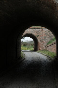 Cobbled path framed by historic arches at Petrovaradin Fortress in Novi Sad, Serbia. Taken in 2025, this photo highlights symmetry, depth, and the blend of light and shadow in old architecture.