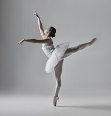 Ballerina, dance and woman with stretching in studio for performance art, skill and balance in routine. Creative, elegance and ballet with dress for freedom, flexibility and talent on gray background