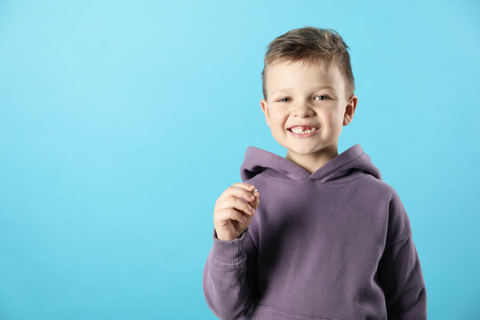 Cute little boy with missing tooth on light blue background, space for text. Waiting for tooth fairy