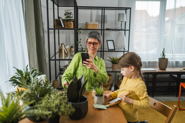 Grandma take a photo of grandchild while she transplant flowers