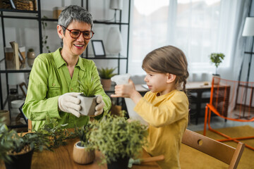 Grandmother with granddaughter transplant and watering flowers at home
