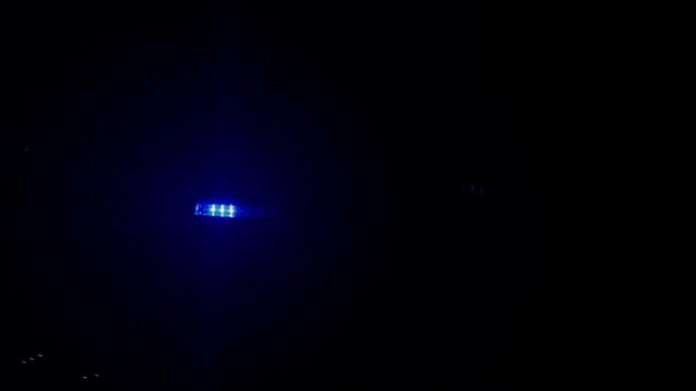 Blue emergency light bar glowing on a police car roof at dark night. Flashing blue LED siren light bar of emergency vehicle in the darkness concept of security, crime scene and law enforcement. 