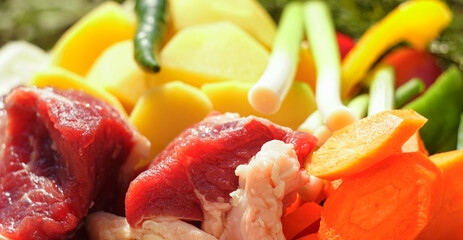 In the lap of nature Raw meat, potatoes, onions and other vegetables in a bowl on a fire