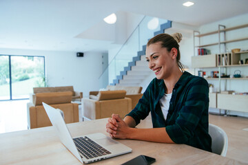Woman sitting in living room using laptop looking at cam talk by video call with business friend relatives, head shot. Job interview answering questions