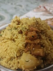 A flavorful Vangi Bhat from Maharashtra, featuring rice cooked with brinjals, potatoes, and aromatic spices. Garnished with coriander, its yellow hue hints at turmeric and traditional seasoning.