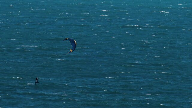 Distant view of a man kitesurfing on a sunny day