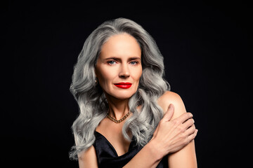 Fototapeta premium Glamorous mature woman with gray hair in a glamorous evening dress on a dark background
