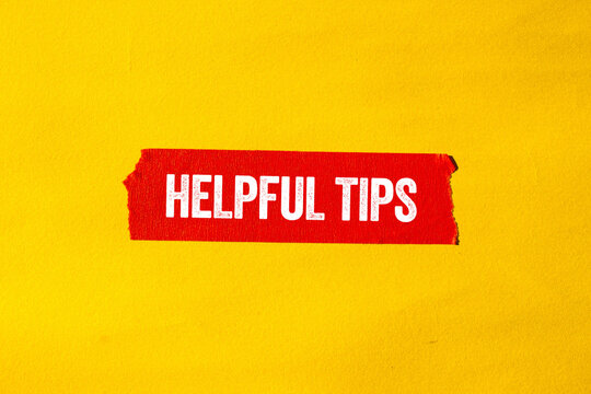 Helpful tips message written on ripped torn red paper tape on yellow background. Conceptual helpful tips symbol. Copy space.