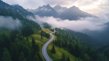 Aerial View of Winding Mountain Road Through the Alps with Snow-Capped Peaks and Morning Fog
