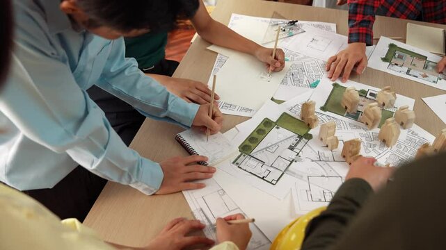 Architect and safety engineer discussion about building construction use blueprint on table with architectural document, measurement tool and wooden block scatter around at modern office. Delineation.