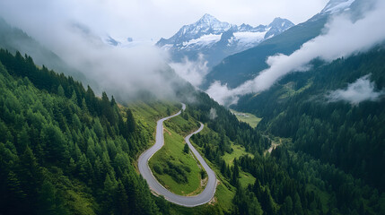 Aerial View of Winding Mountain Road Through the Alps with Snow-Capped Peaks and Morning Fog