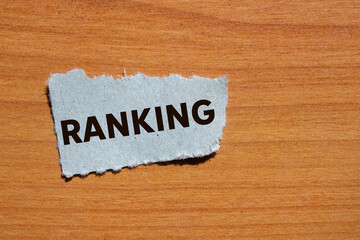 Ranking message written on ripped torn grey paper piece on wooden background. Conceptual ranking...