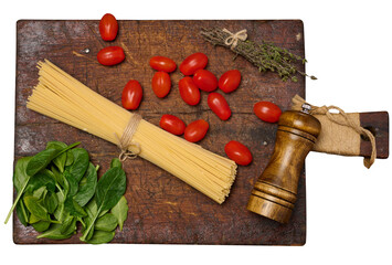 Bundle of raw pasta tied with twine, surrounded by cherry tomatoes, fresh spinach leaves, thyme,...