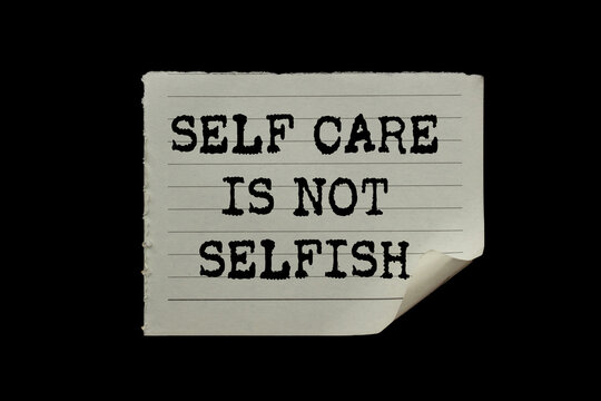 Self care is not selfish message written on ripped torn paper piece on black background. Conceptual self care is not selfish symbol. Copy space.