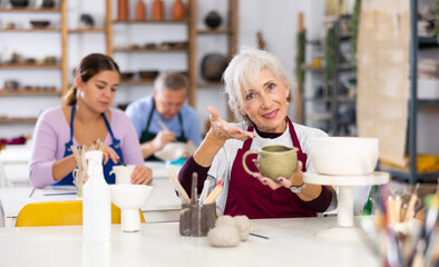woman at potter's master class finished painting vase that she had made earlier