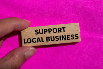 Support local business message written on wooden block on pink background. Conceptual support local...