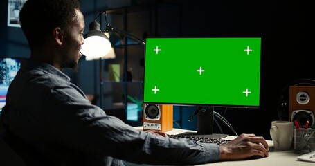 African american adult working from home using chroma key mockup, reviewing statistical data to compare supply and demand numbers. Sitting at desk and writing on his computer. Camera A.