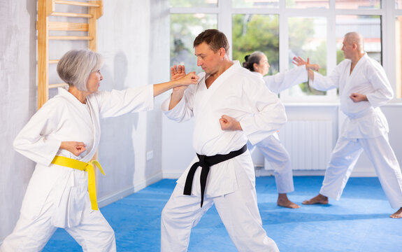 Dynamic photo capturing energy and focus of senior athletics students people fighting in karate class. Obtaining black belt, advanced training, highest dan of martial arts. Sport to max. - Powered by Adobe