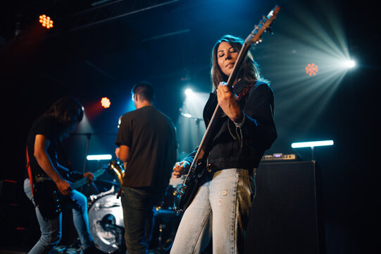 Female musician playing bass guitar during live rock concert