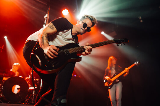 Guitarist performing live on stage with bandmates - Powered by Adobe