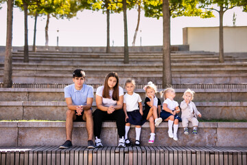 Obraz premium Group of Children and Teens Sitting on Bench in Outdoor Amphitheater