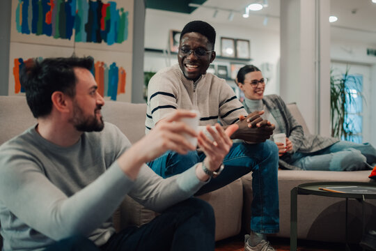 Coworkers enjoying coffee break and sharing stories in modern office