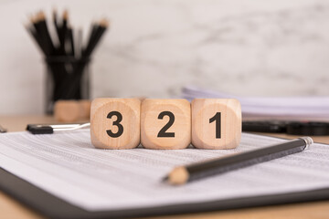wooden blocks with numbers "3, 2, 1" on financial documents, symbolizing countdown and business planning
