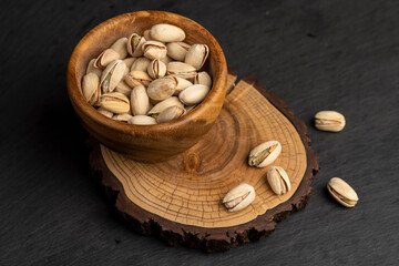 fried unpeeled pistachio nuts in a wooden bowl with cracked shells