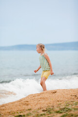 Cheerful girl running barefoot along the sandy beach at the seashore