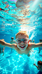 Naklejka premium Portrait of a boy swimming underwater in a pool. A joyful child looks at the camera.