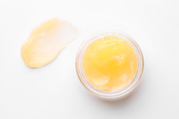 Jar and sample of lip balm on white background, top view