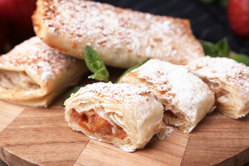 Tasty apple strudels with powdered sugar and mint on table, closeup