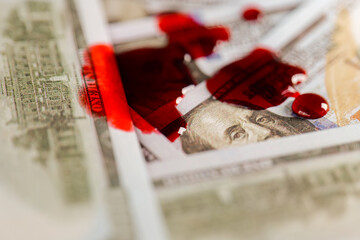 Bloody finance.Drops of blood on dollars.Benjamin Franklins face on the bill is in blood.Money with...