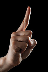 Close-up of human hand pointing with index finger on black background. Gesture of direction, touch...
