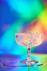 fresh drink in a modern cocktail glass on colorful bright shiny background in night club or beach bar, added film grain, selective focus