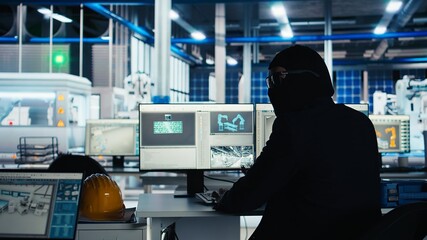 Masked hacker sneaking into solar panel plant at night, inserting USB stick into computer to steal...