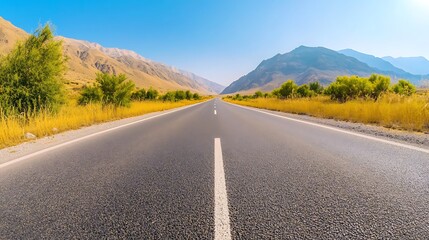 Naklejka premium Scenic Empty Road Through Parched Landscape with Mountains Under Clear Blue Sky