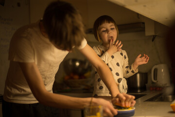 Two children are busily engaged in preparing food together in a cozy kitchen setting during night...