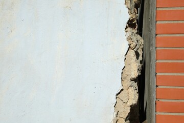 Old white building near new brick wall. Earthquake aftermath