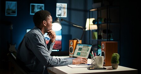 Focused remote worker balancing freelance tasks and researching data online, drafting notes and...