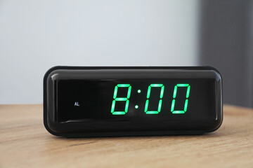 Digital alarm clock showing 8:00 o'clock on bedside table indoors